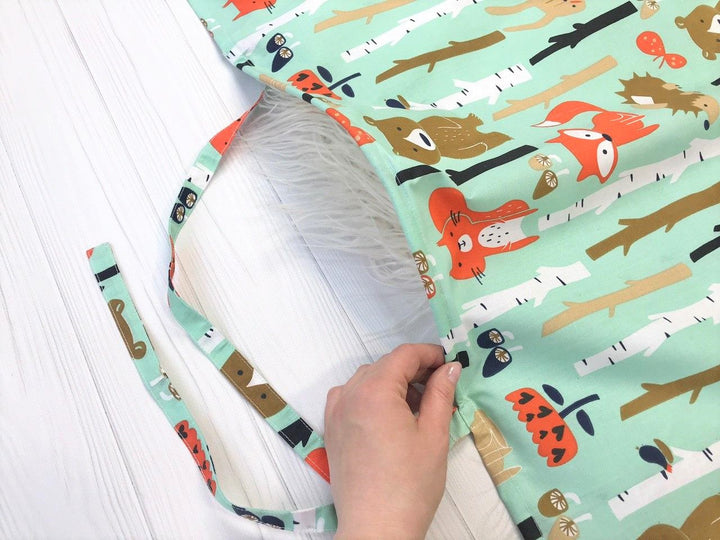 Жінка використовує стильну та зручну накидку для годування, що забезпечує комфорт та конфіденційність під час грудного вигодовування на природі.