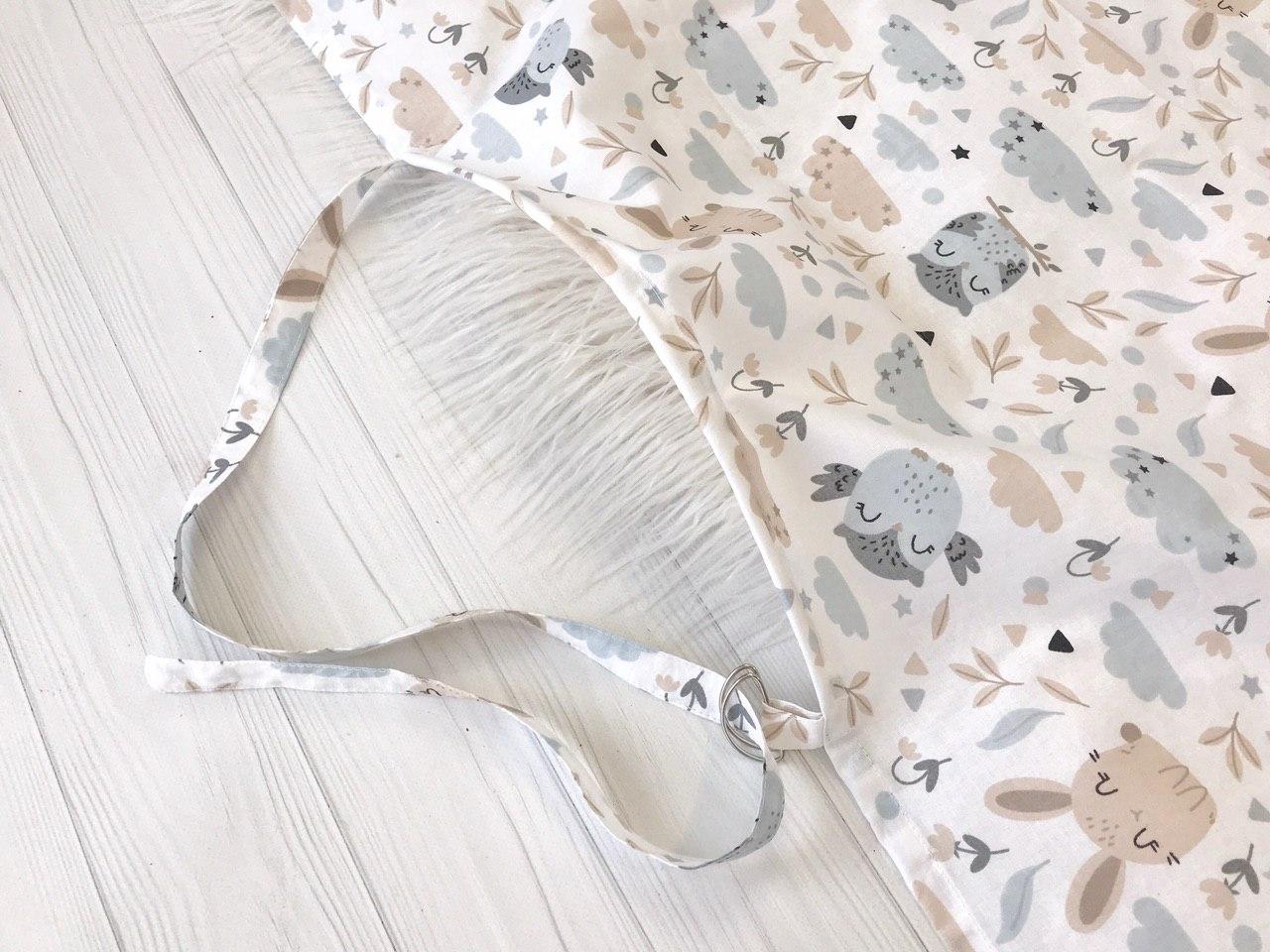 Жінка використовує стильну та зручну накидку для годування, що забезпечує комфорт та конфіденційність під час грудного вигодовування на природі.