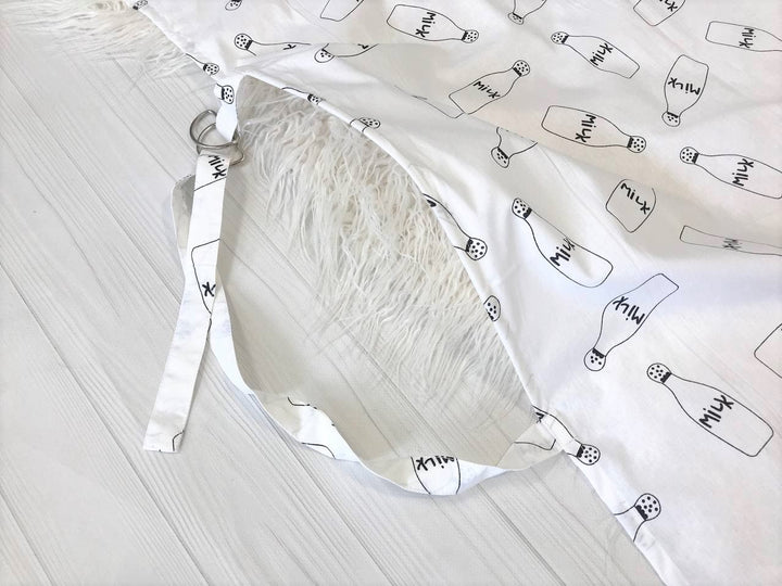 Жінка використовує стильну та зручну накидку для годування, що забезпечує комфорт та конфіденційність під час грудного вигодовування на природі.